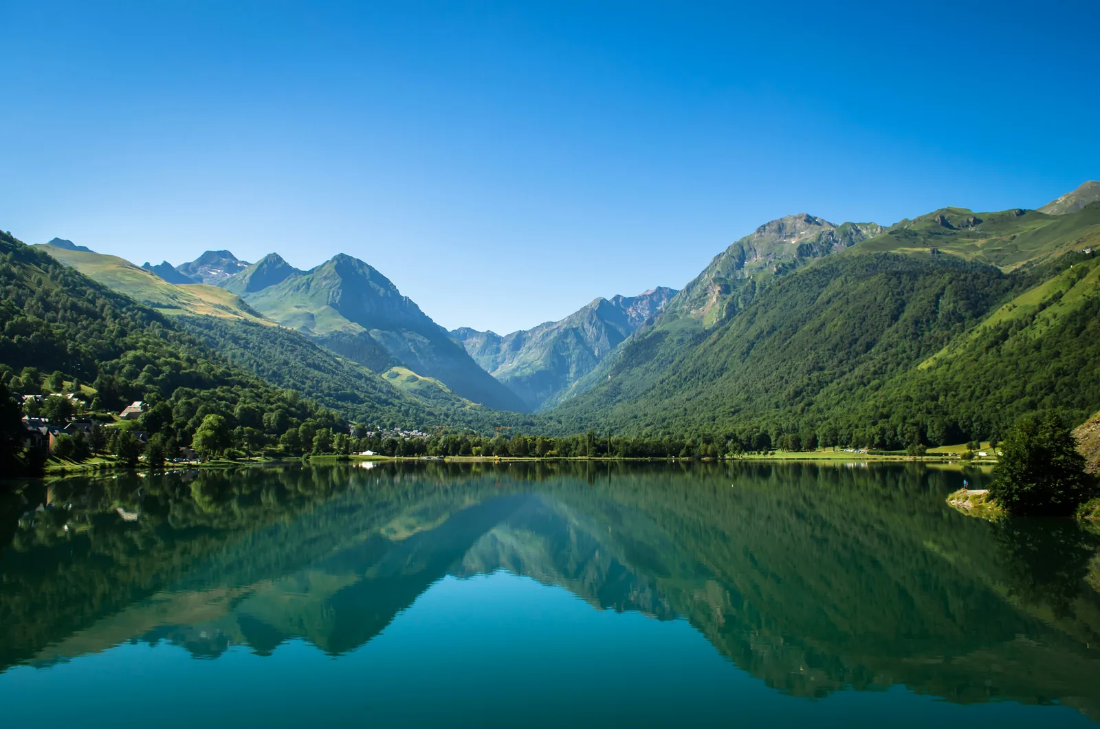 Vue du lac de Génos-Loudenvielle dans la vallée du Louron avec montagnes, village et environnement naturel des Hautes-Pyrénées